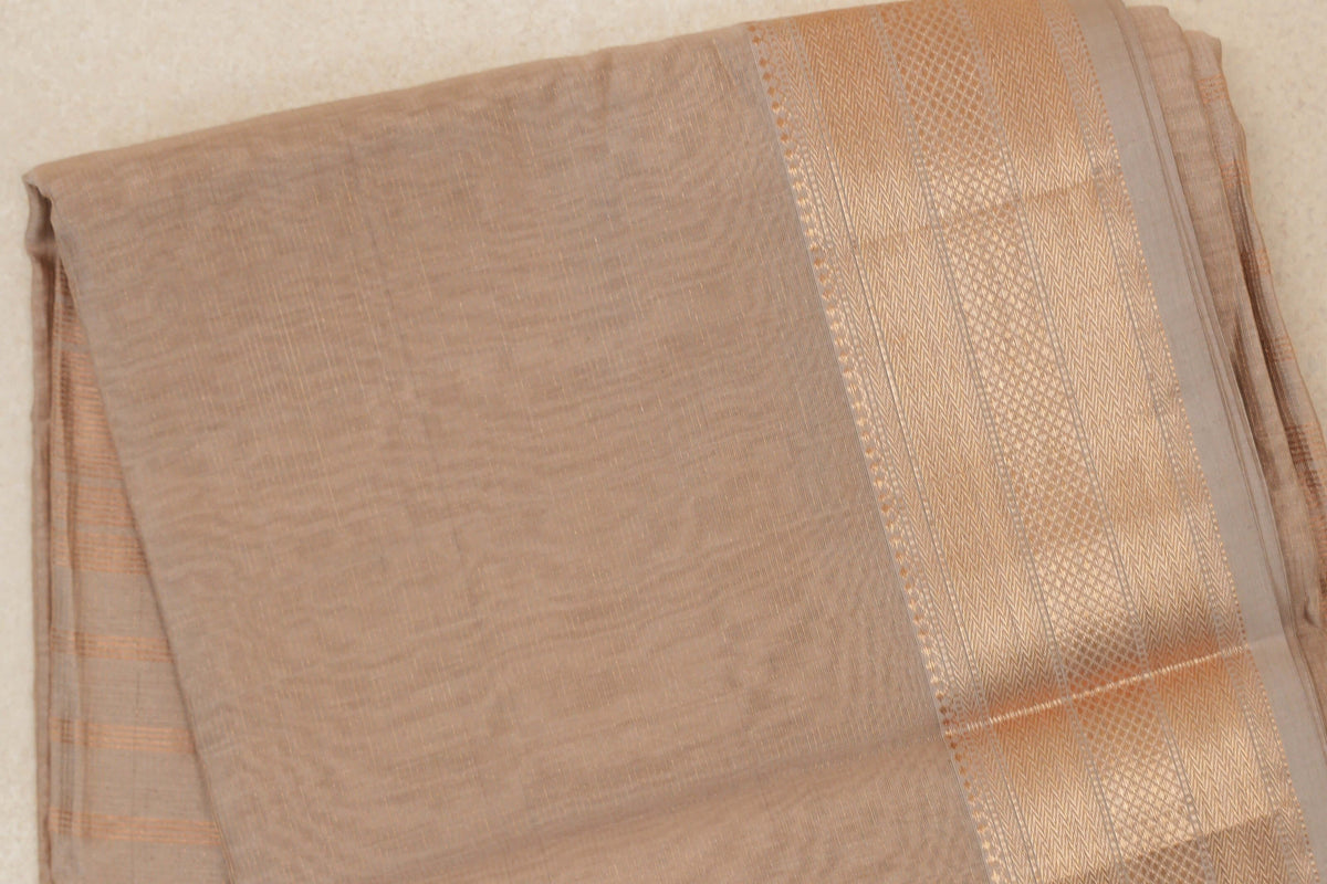Folded Dark Sandal Beige Maheshwari silk cotton saree showing a plain, finely textured body and a wide, lustrous patterned border.