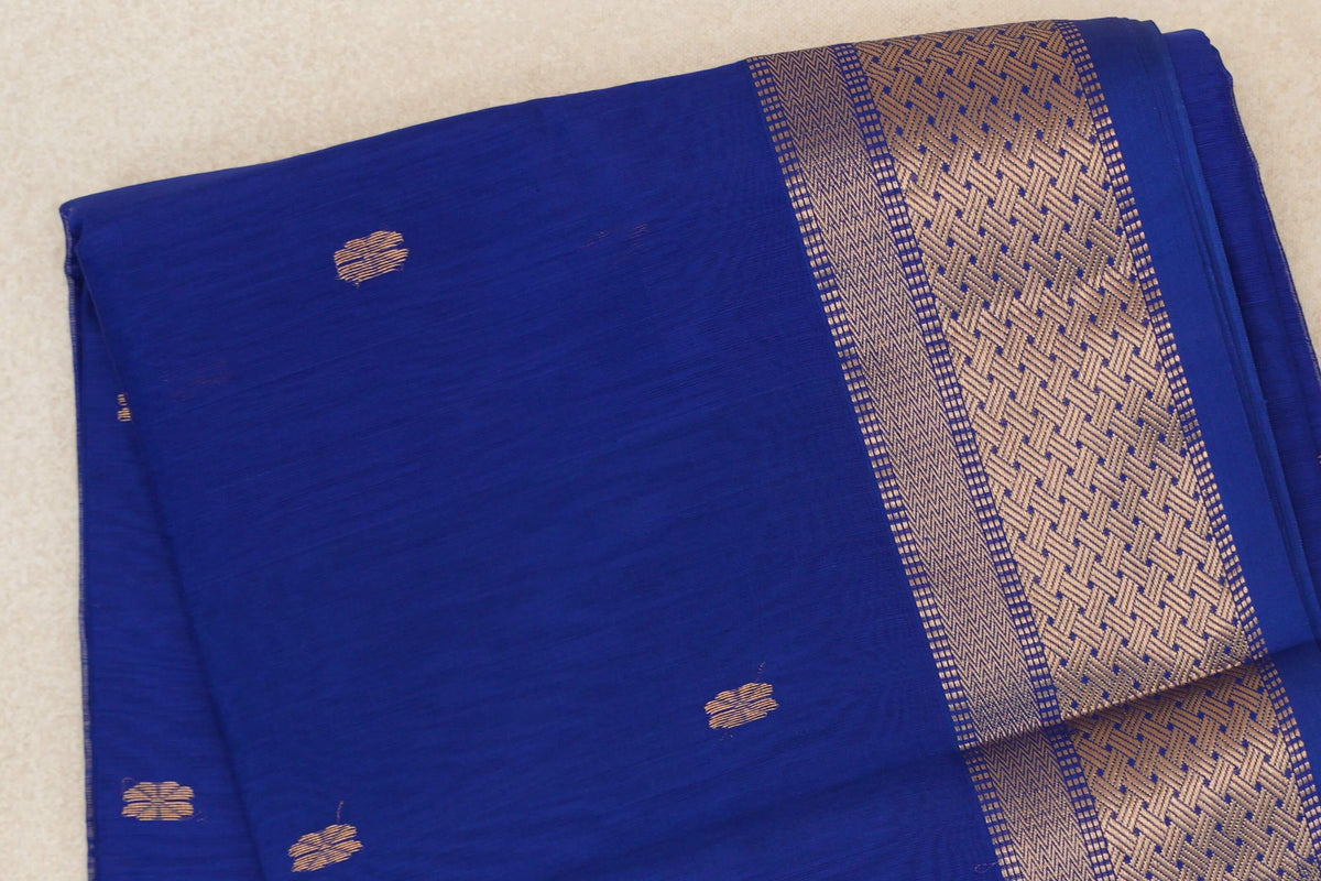 Folded bright royal blue Maheshwari silk cotton saree with scattered gold motifs and a wide geometric gold border.
