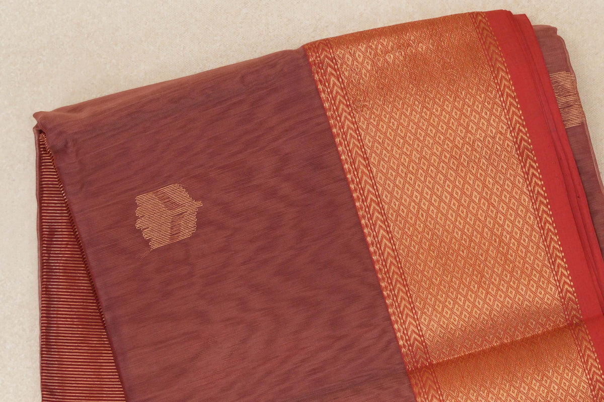 Folded dusty rose Maheshwari silk cotton saree with a small gold woven accent, a broad gold-patterned border and red selvedge.