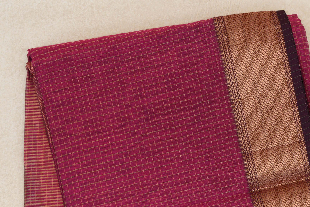 Folded Rani Pink Maheshwari silk cotton saree with fine gold-toned checks and a broad textured border edged in Deep Rani Pink.