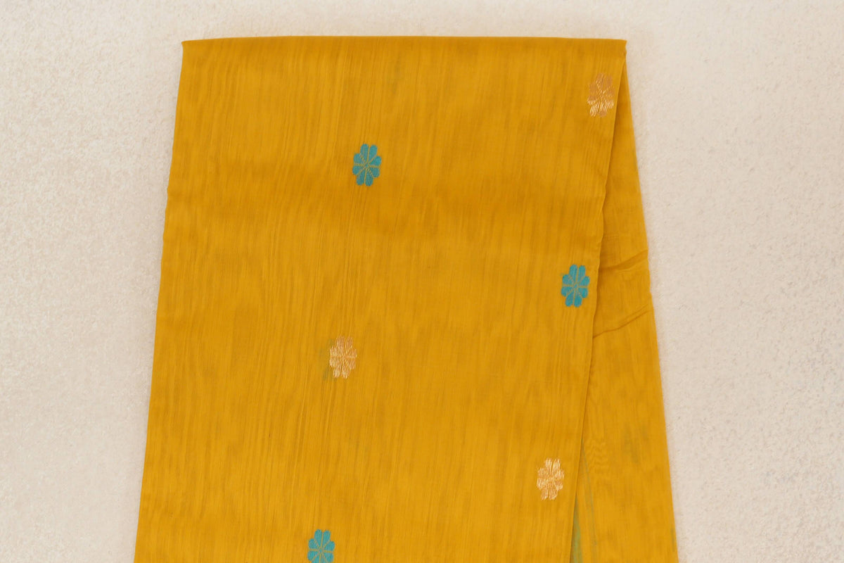Folded mango yellow Maheshwari silk cotton saree body with scattered turquoise blue and cream floral motifs and a fine vertical texture.
