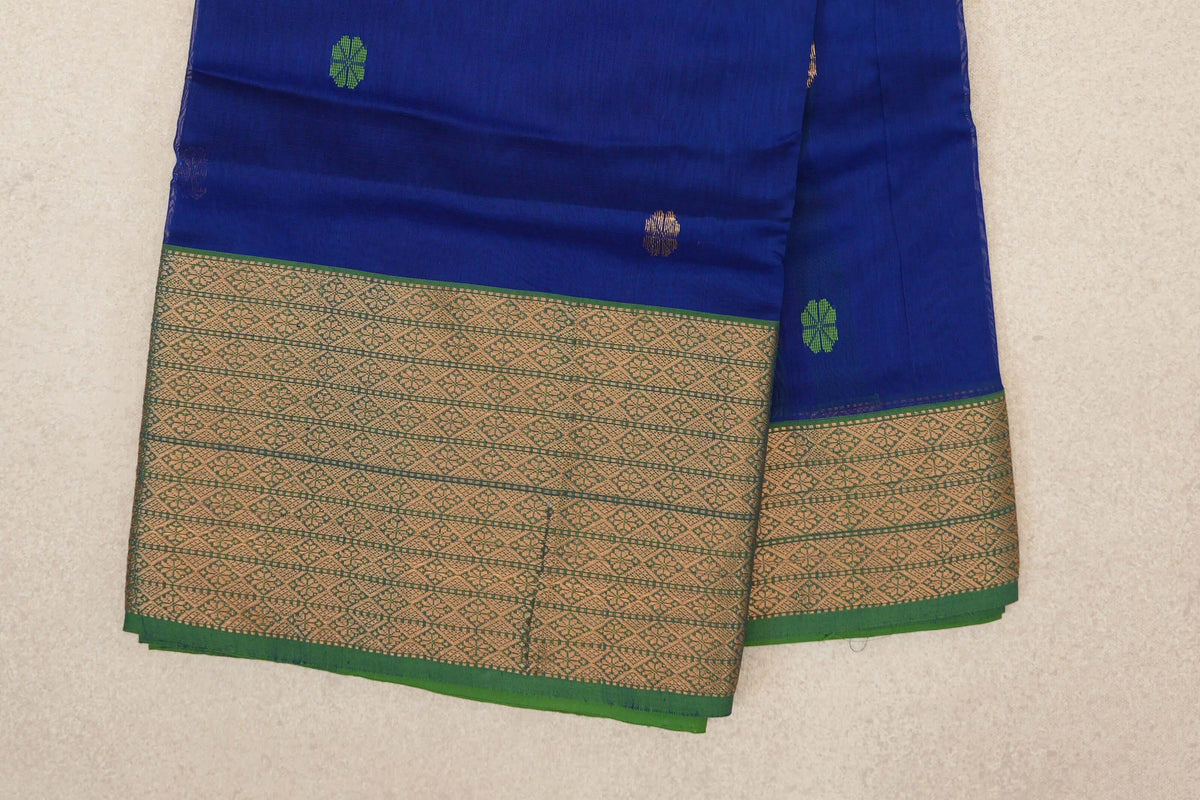 Folded Maheshwari silk cotton saree showing a deep royal blue body with small green and gold motifs and a wide, gold-patterned forest green border.