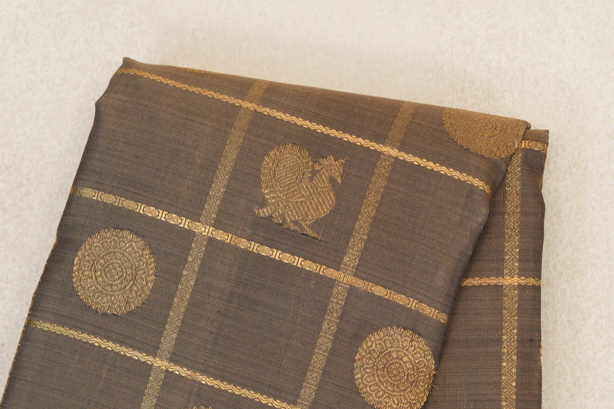 Folded olive green Kanjivaram silk saree with gold circular motifs and fine intersecting gold stripes.