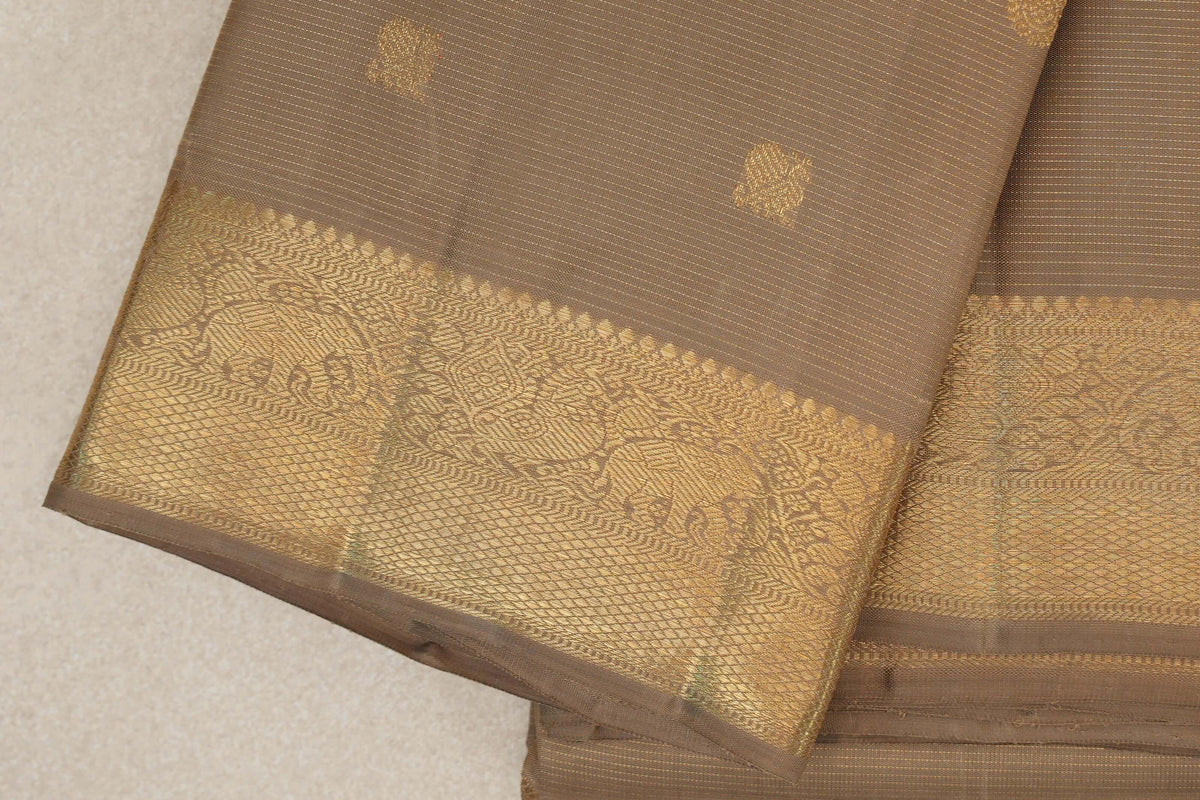 Folded greenish beige Kanjivaram silk saree showing fine gold stripes, small woven motifs and a broad gold border with elephants.