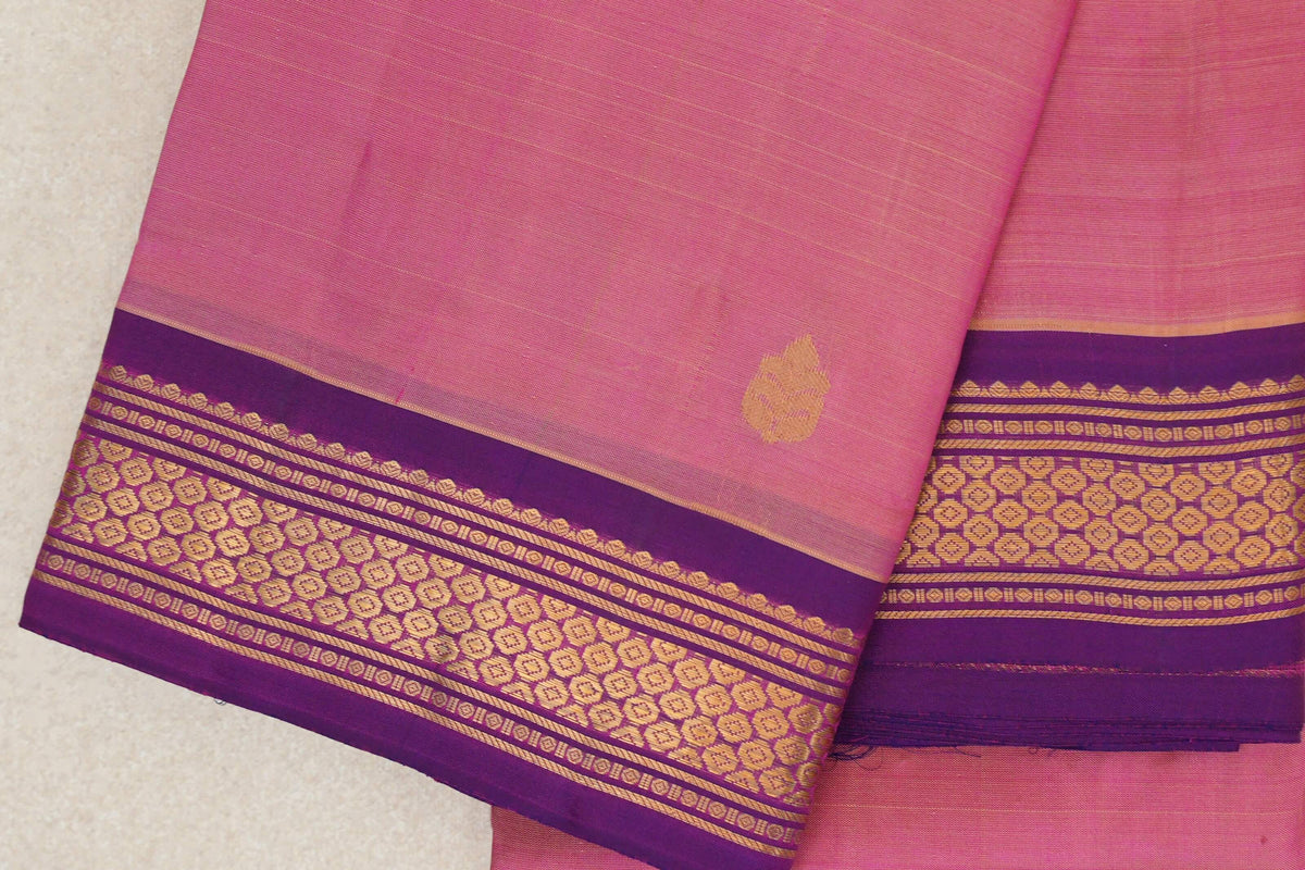 Folded rose pink lightweight Kanchipuram silk saree with a small gold-toned leaf motif and purple borders patterned in gold.
