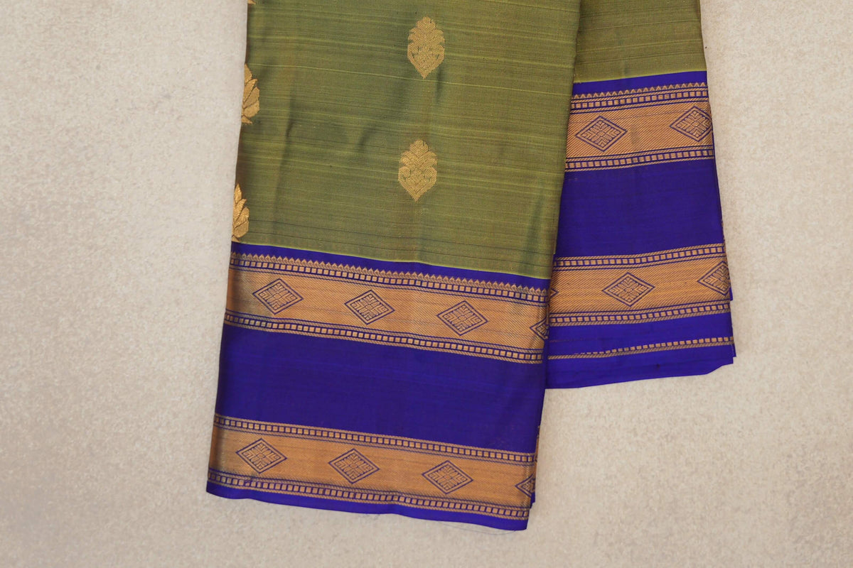 Folded olive green lightweight Kanchipuram silk saree with gold leaf motifs and royal blue borders edged with gold diamond-patterned bands.