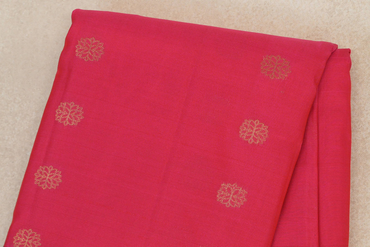 Folded bright rani pink lightweight Kanchipuram silk saree, showing the body with evenly spaced gold floral motifs.