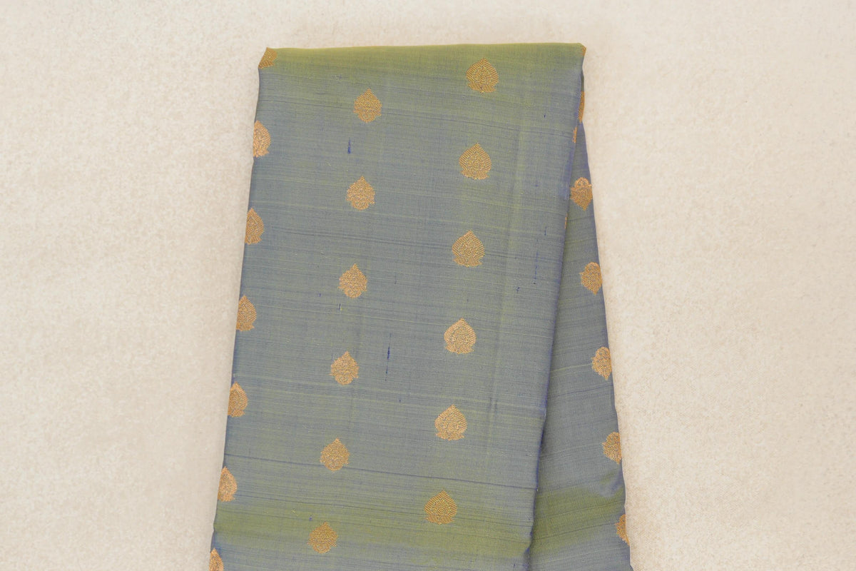 Folded yellowish green lightweight Kanchipuram silk saree, showing evenly spaced small gold teardrop motifs across the body.