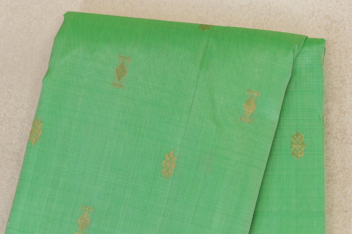 Close-up of a folded mint green Kanchipuram silk saree body with spaced gold diamond and clustered motifs.