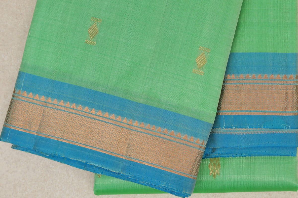 Folded lightweight Kanchipuram silk saree with a mint green body, small gold motifs and a light turquoise blue border with gold geometric detailing.