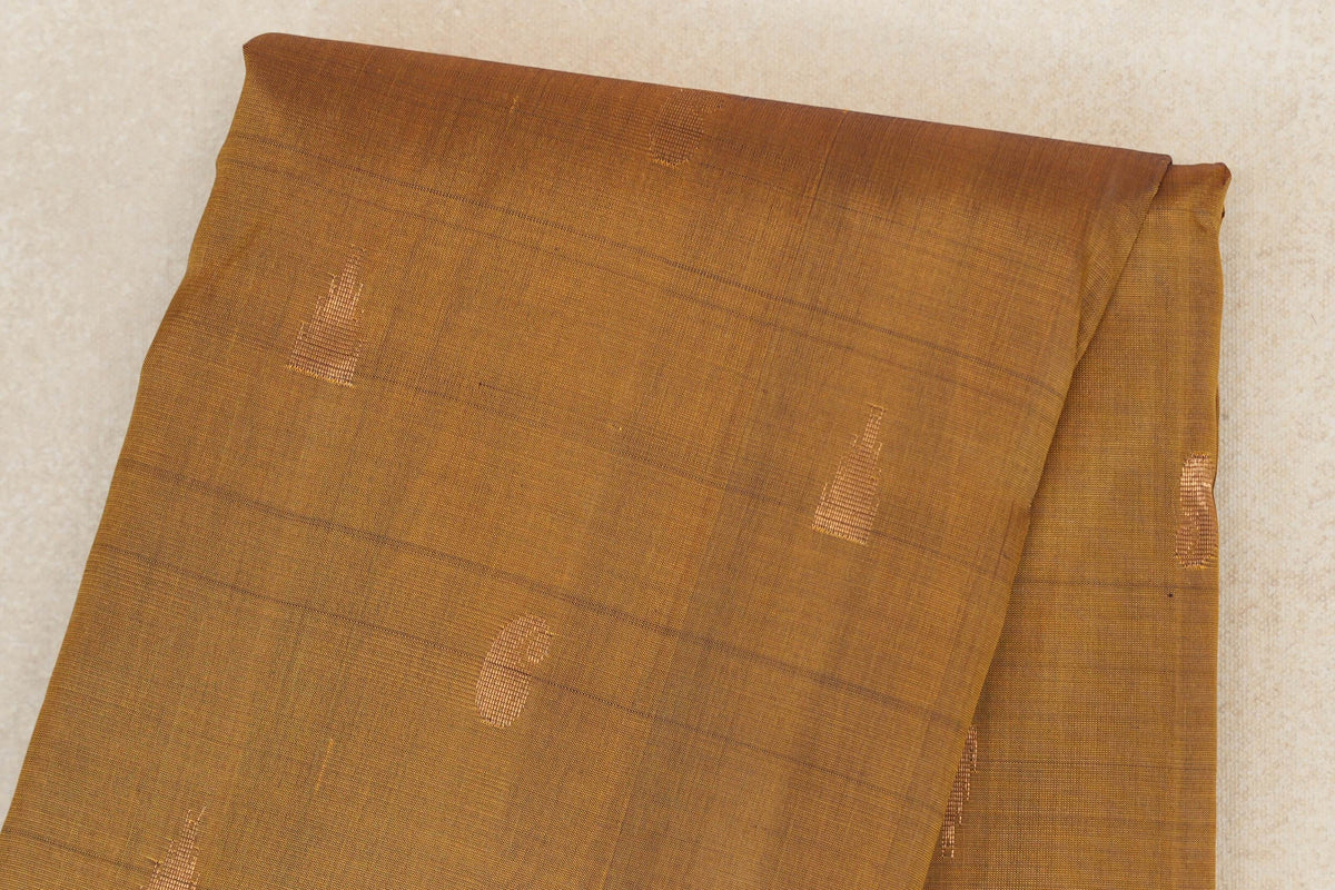 Close-up of a folded oil mustard Kanchipuram silk saree body with small gold-toned woven accents and subtle horizontal lines.