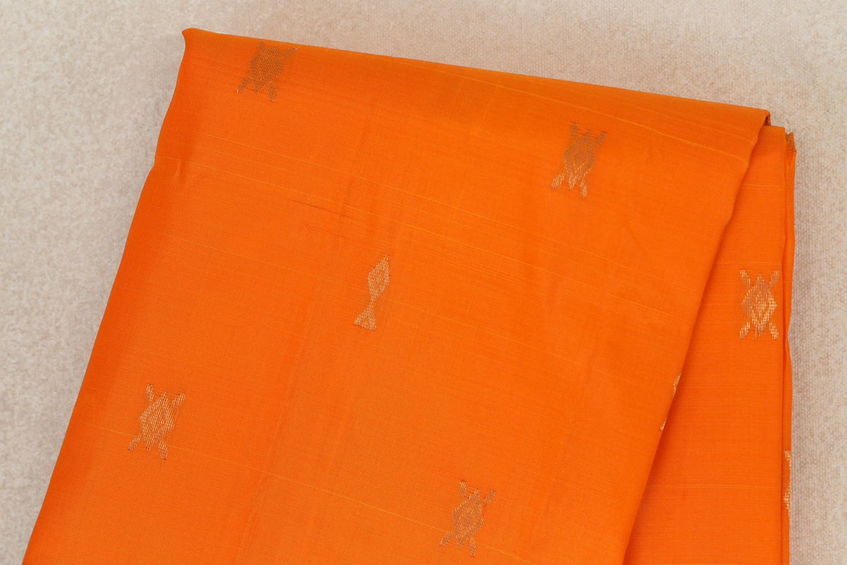 Folded bright orange lightweight Kanchipuram silk saree, showing the body with scattered small gold zari motifs.