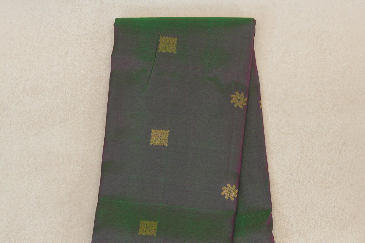 Folded lightweight Kanchipuram silk saree showing a green and pink body with scattered gold square and floral motifs.