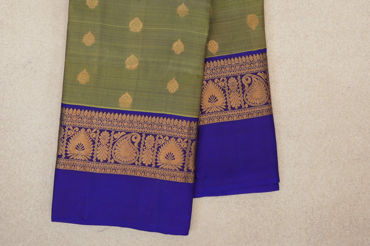 Folded lightweight Kanchipuram silk saree with an olive green body, scattered gold motifs and royal purple borders patterned with gold paisleys and flowers.