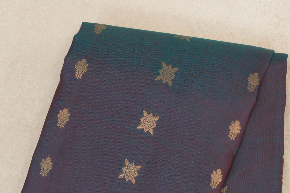 Folded body of a lightweight Kanchipuram silk saree in teal blue and red, with scattered gold floral and star-shaped motifs.