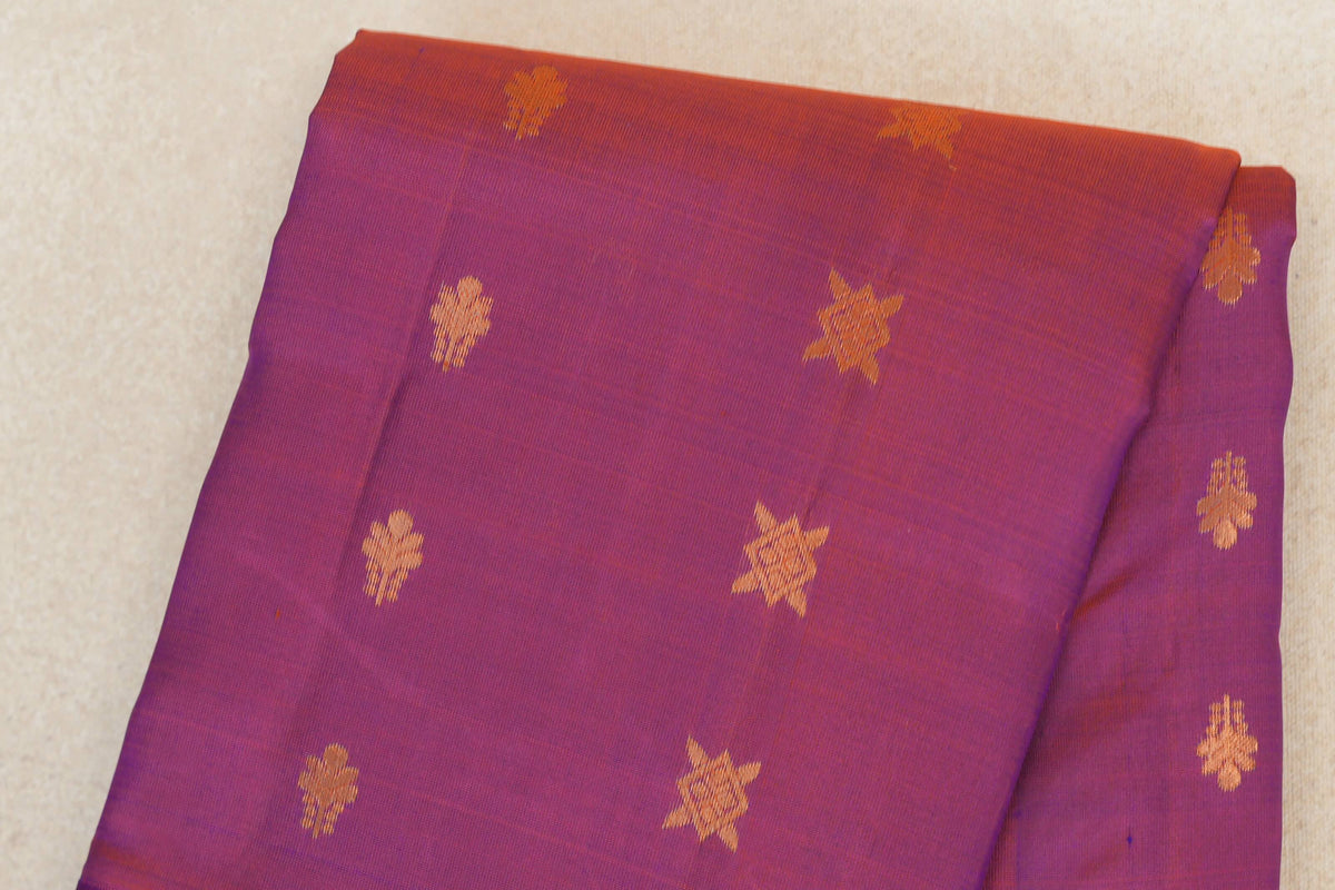 Folded light weight Kanchipuram silk saree in purplish blue and red, with scattered gold-colored floral and star motifs.